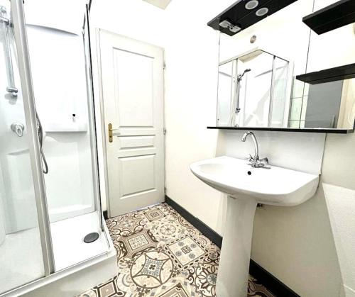 une salle de bain blanche avec un lavabo et une douche dans l'établissement Les Jours Calmes, studio chaleureux, à Limoges