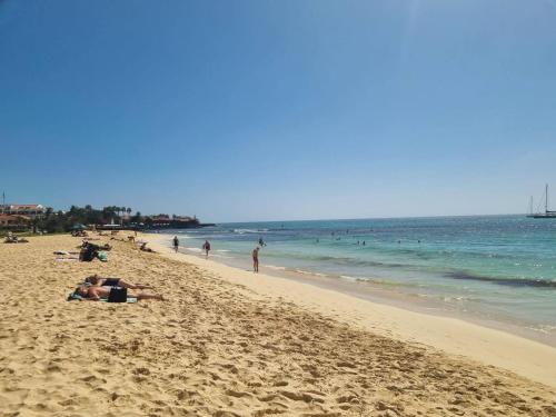 a beach with people laying on the sand and the ocean at Animoss! Apartments - 10 modern apartments near city center & beach in Santa Maria