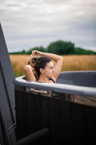 a woman is taking a bath in a bath tub at Wilder Retreats - A Frame Cabins in Haverfordwest