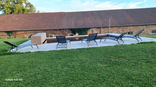 a group of chairs and a table in the grass at Gîte La Maijou d'Aômés in Saint-Martin-le-Vieux