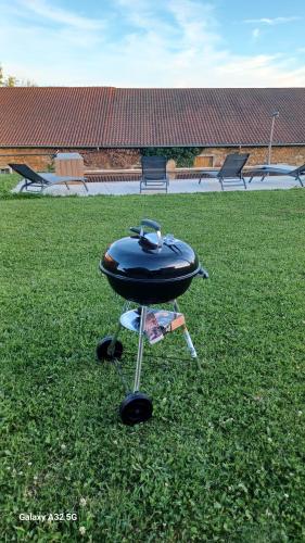 a grill sitting on the grass in a field at Gîte La Maijou d'Aômés in Saint-Martin-le-Vieux