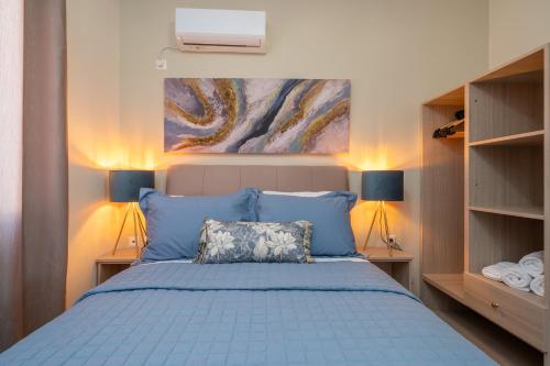 a bedroom with a blue bed with a painting on the wall at Seaside Euphoria Kefalonia in Ayia Evfimia