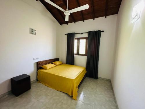 a bedroom with a bed with yellow sheets and a window at Hidden Heaven Villa in Beruwala