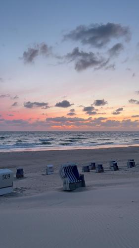 ヴェスターラントにあるPrivates Domizil auf Sylt in Strandnäheのビーチチェアのグループでの夕暮れ時