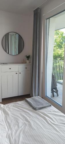 a bedroom with a bed with a mirror and a balcony at Apartament Cuma - zacumuj w Pucku in Puck