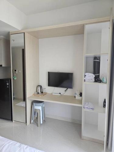 a room with a desk with a television in it at Green Sedayu Apartment Suite by Ellison in Jakarta