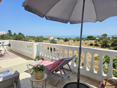 a patio with an umbrella and a chair on a balcony at Sunshine, casa de campo e praia, estilo e conforto, espaço e privacidade, perfeita para as suas férias em Olhão in Moncarapacho