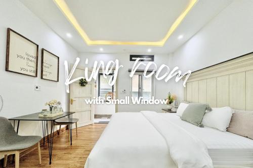 a large white bed in a room with a table at Cloudy Homestay Hoi An in Hoi An