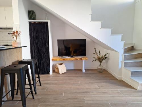 a living room with a tv on a table and stairs at Casa rural El Rincón de la Yedra in Setenil