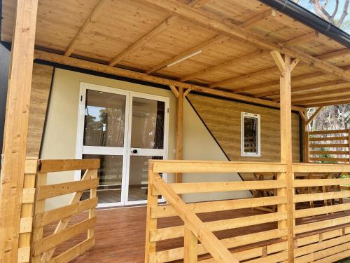 a wooden pergola on a house with a porch at ISOLA VERDE Camping Village in Nettuno