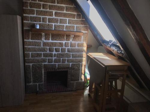Cette chambre dispose d'une cheminée en briques, d'un bureau et d'une table. dans l'établissement Studio parisien plein de charme, à Paris