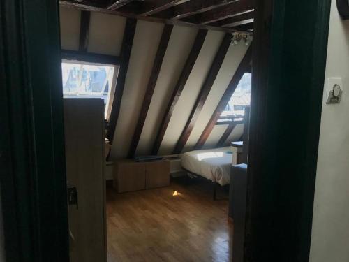 Cette chambre mansardée comprend un lit et une fenêtre. dans l'établissement Studio parisien plein de charme, à Paris