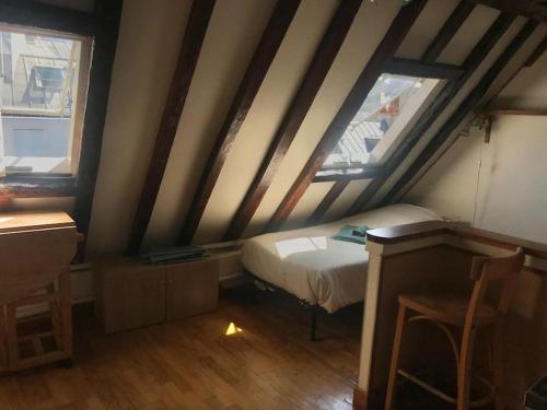 Cette chambre mansardée comprend un lit et deux fenêtres. dans l'établissement Studio parisien plein de charme, à Paris