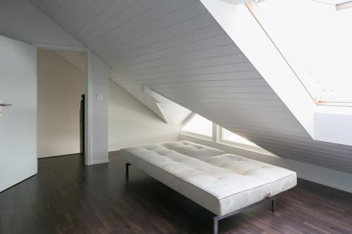 Una cama blanca en una habitación con ventana. en 30C Route d'Arzier, en Saint-Cergue