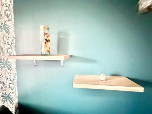 un mur avec deux étagères en bois sur un mur bleu dans l'établissement Le Beaupeyrat, chaleureux et calme, à Limoges