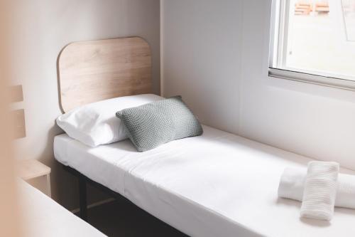 a small room with a bed with a mirror at ISOLA VERDE Camping Village in Nettuno