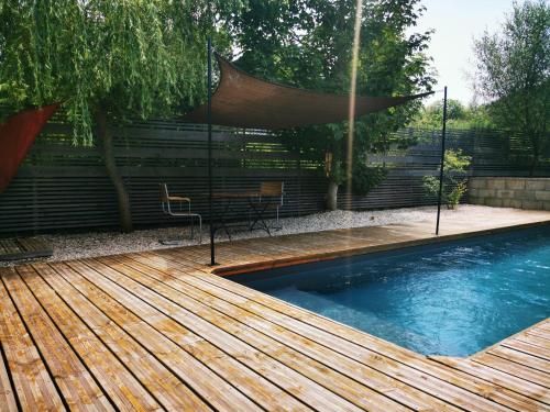 une piscine avec une terrasse en bois à côté d'une clôture dans l'établissement Les Gîtes Vu d'Ici, à La Chapelle-en-Vercors