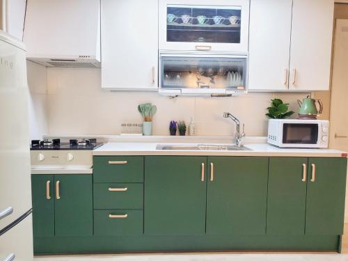 a kitchen with green cabinets and a microwave at Indeogwon Hue Stay in Anyang