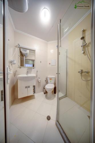 a bathroom with a shower and a toilet and a sink at Aparthotel Forest Nook in Pamporovo