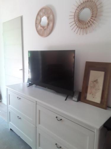 - une commode blanche avec une télévision à écran plat dans l'établissement Chambre d'hôte équipée avec terrasse verdoyante, à Saint-Rémy-de-Provence