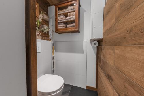 La salle de bains est pourvue de toilettes blanches et d'une porte en bois. dans l'établissement Le Petit Rêve - Lac de Montriond, à Montriond