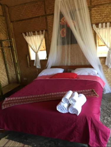 a bedroom with a red bed with two pairs of underwear at Tulip Resort Pai in Pai