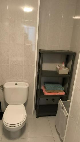 a bathroom with a white toilet and a shelf at O fogar de Sara in O Grove