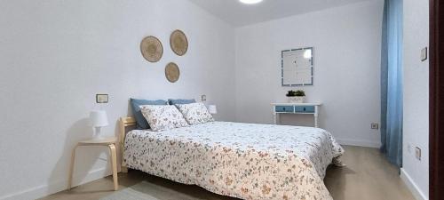 a white bedroom with a bed and a table at O fogar de Sara in O Grove
