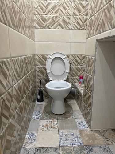 une salle de bain avec toilettes et un mur carrelé dans l'établissement Appartement au calme proche centre, à Alès