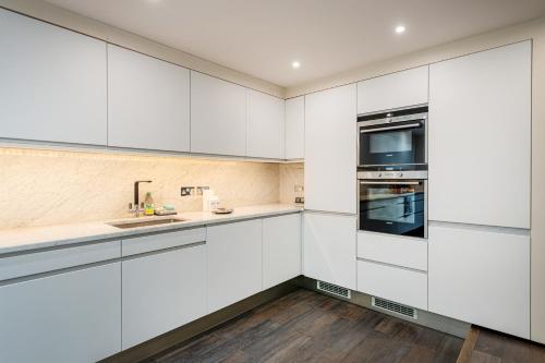 a kitchen with white cabinets and a sink at Luxury 3BR Home in Belgravia, Near Victoria in London