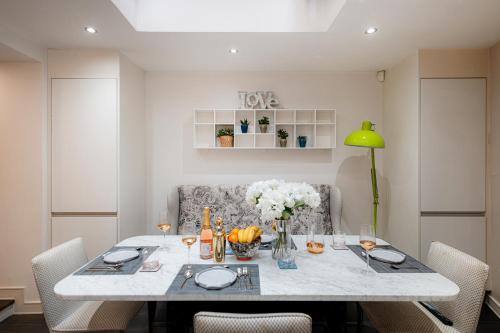 a dining room table with chairs and a green lamp at Luxury 3BR Home in Belgravia, Near Victoria in London