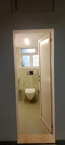 a bathroom with a white toilet and a window at Bendre's Farm Stay-Neral in Neral