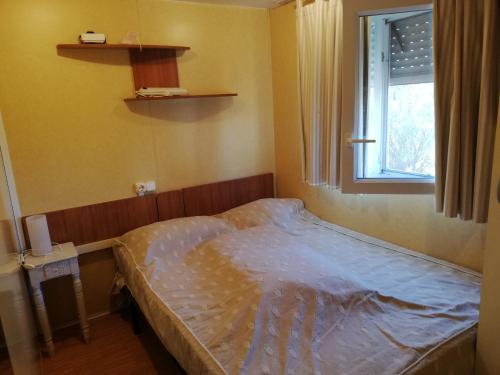 un petit lit dans une chambre avec une fenêtre dans l'établissement Familial, à Hyères