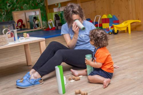 a woman and a little girl sitting on the floor at Alpholiday Dolomiti Wellness & Family Hotel in Dimaro