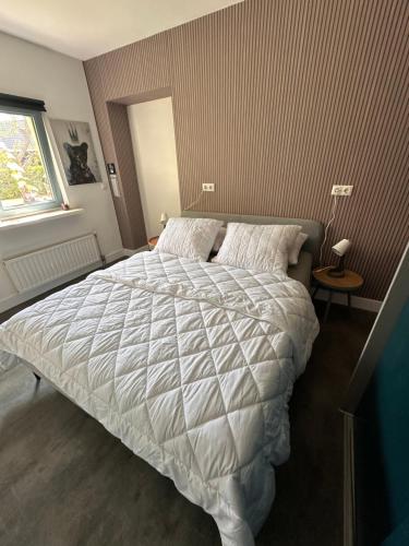 a bedroom with a bed with a white comforter at B&B Het Kleine Huisje met Hottub in Emmen