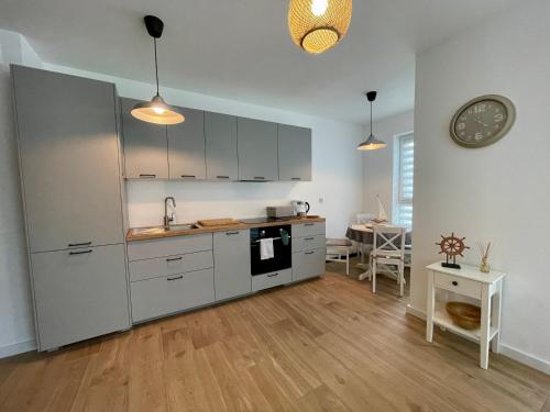 a kitchen with white cabinets and a table and a clock at Oaza Przystań in Giżycko