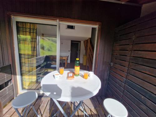 une petite table blanche avec des boissons sur un porche dans l'établissement 3 chambres pied piste, à Aragnouet