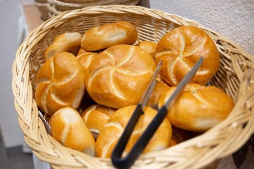 a basket full of buns with tongs in it at Hotel Garni Waldschlössl in Ischgl