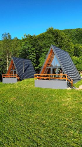 two houses on top of a grassy hill at Rock Valley Cabins A-frame in Ibăneşti