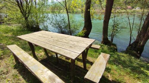a picnic table and two benches in front of a river at Vagabundo Home in Rogačica