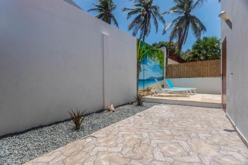 a patio with a wall and a chair and palm trees at Casa Trankilo in Paradera