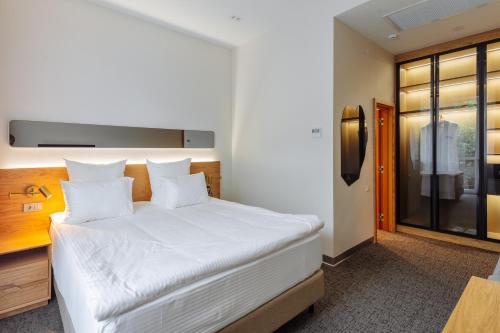 a bedroom with a white bed with a tv on the wall at Old Ijevan Boutique Hotel in Ijevan