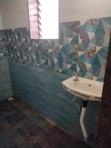 ein Badezimmer mit einem Waschbecken und einer Mosaikwand in der Unterkunft Annapurna beach resort in Malvan