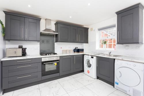 a kitchen with black cabinets and a washer and dryer at Lancers Close House in Leyland