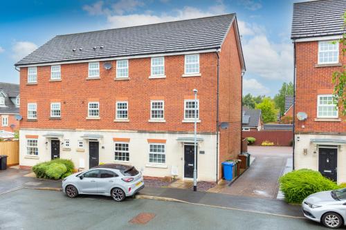 a red brick house with a car parked in a parking lot at Lancers Close House in Leyland