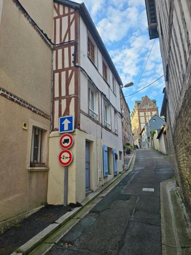 Une allée avec un panneau indiquant la rue sur le côté d'un bâtiment dans l'établissement Petit Duplex, à Honfleur