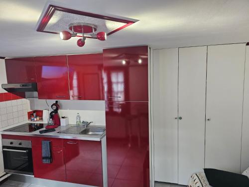 - une cuisine rouge avec des placards blancs et un évier dans l'établissement Petit Duplex, à Honfleur