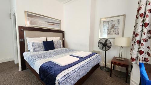 a bedroom with a bed with blue and white pillows at Gatwick Castle B&B in Horley