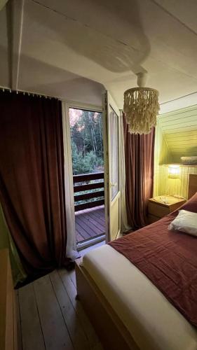 a bedroom with a bed and a window with a chandelier at Leszczynowy domek nad jeziorem in Dobre Miasto