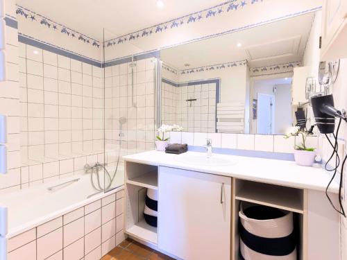 une salle de bain avec un lavabo, une baignoire et un miroir dans l'établissement Manoir de Duke - piscine, parc arboré, clim, parking gratuit, à Cannes